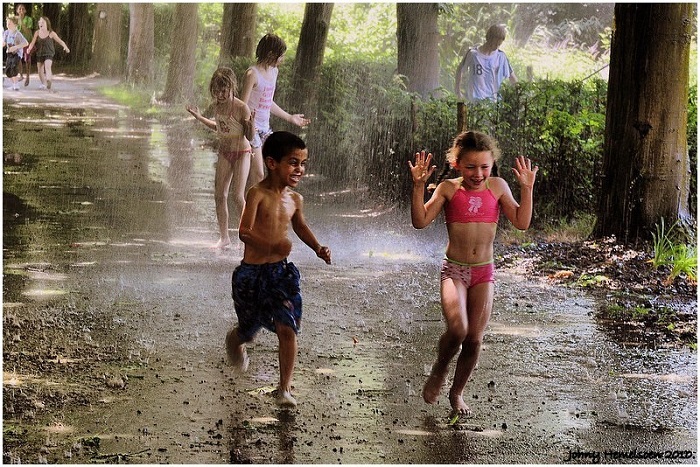 niños se les ve felices y complacidos cuando juegan bajo la lluvia 